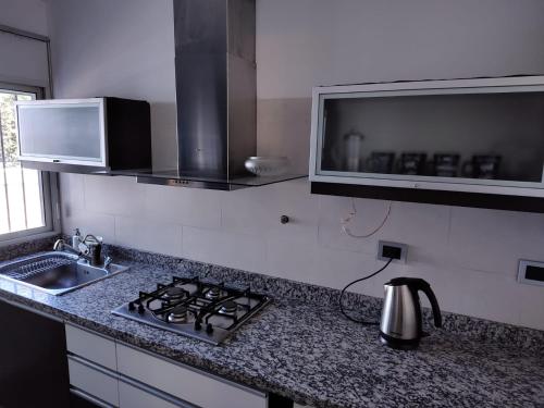 cocina con fogones, fregadero y microondas en Bombal 1 a pasitos de Arístides en Mendoza
