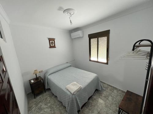 Habitación blanca con cama y ventana en Casa Rural Guzman, en Setenil