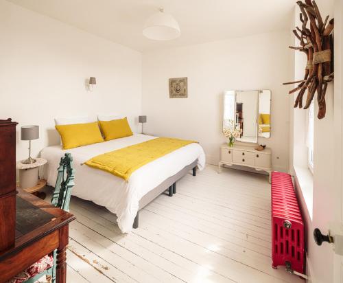 a bedroom with a bed with yellow pillows and a mirror at La Cantellerie in Courseulles-sur-Mer