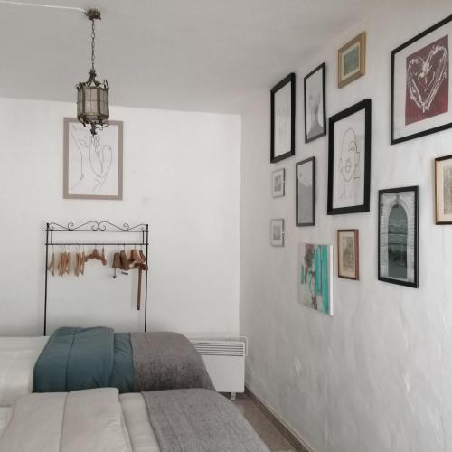 a white bedroom with a bed and pictures on the wall at Casa do Cabeço - Termas da Sulfúrea in Cabeço de Vide