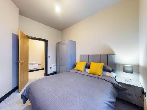 ein Schlafzimmer mit einem großen Bett mit gelben Kissen in der Unterkunft Gibson Manor Apartment 10 in Wallasey