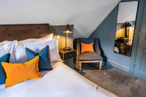 a bedroom with a bed with colorful pillows and a chair at The Ginger Pig in Brighton & Hove