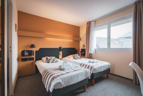 two beds in a room with a window at Hotel bar Saint Christophe in Le Tilleul