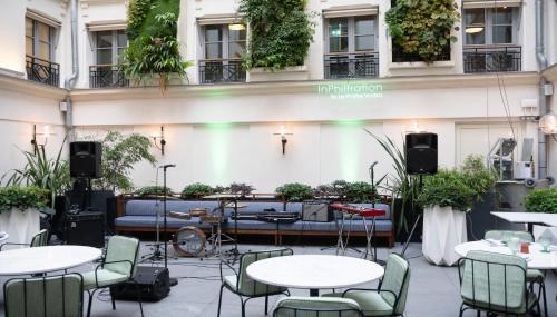 a patio with tables and chairs and a couch at Kimpton - St Honoré Paris, an IHG Hotel in Paris