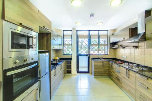a large kitchen with wooden cabinets and stainless steel appliances at Fedha Residences by Trianum in Nairobi