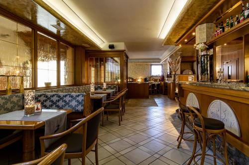 a restaurant with tables and chairs and a bar at Hotel Arcobaleno in Fai della Paganella