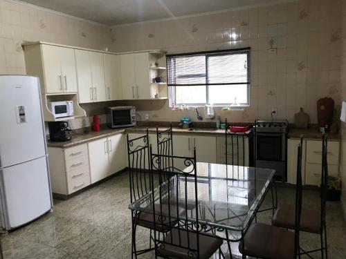 uma cozinha com uma mesa e um frigorífico branco em Casa gigante com vista para o mar e piscina em São Vicente