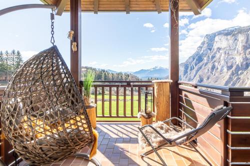 a swing on a porch with a view of mountains at Hotel Arcobaleno in Fai della Paganella