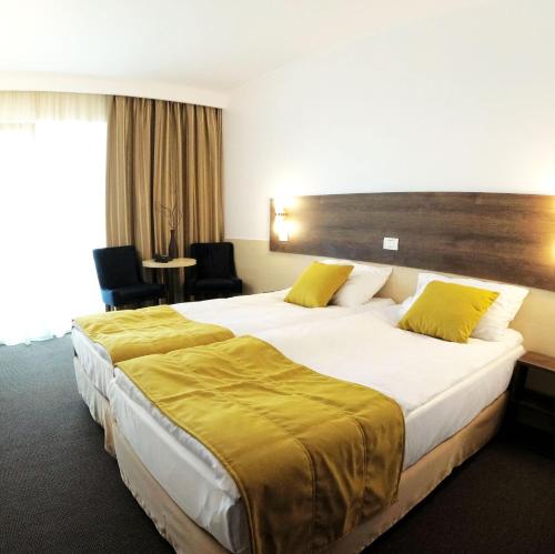 a hotel room with two beds with yellow pillows at Zenith - Top Country Line - Conference & Spa Hotel in Mamaia