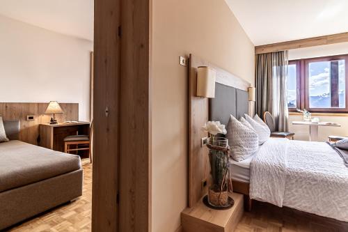 a hotel room with a bed and a desk at Hotel Arcobaleno in Fai della Paganella