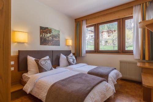 two beds in a room with two windows at Hotel Arcobaleno in Fai della Paganella
