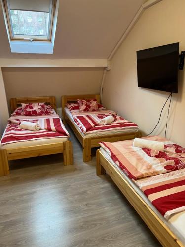 a room with two beds and a flat screen tv at Kiskakas Étterem in Zalaegerszeg