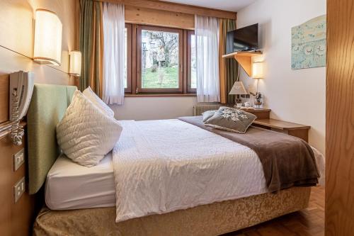 a hotel room with a bed and a window at Hotel Arcobaleno in Fai della Paganella