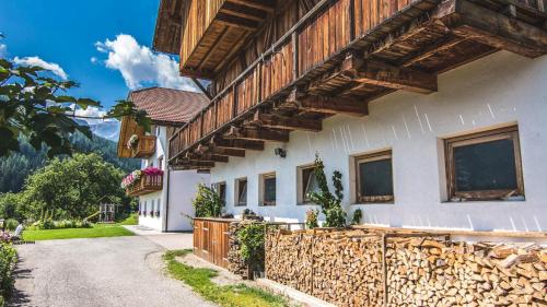 a white house with wooden beams and a fence at Kranebitterhof Apt Edelweiss in Valdaora