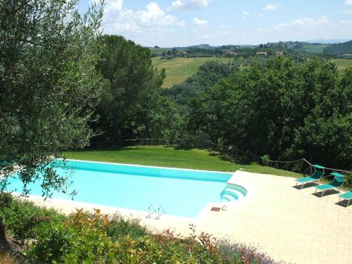 uma grande piscina com cadeiras e árvores em Le Fonti A San Giorgio em Montespertoli
