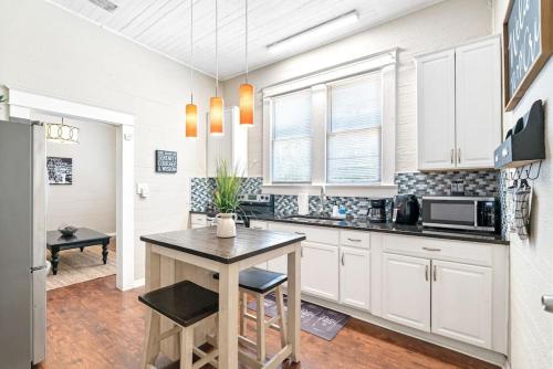 a kitchen with white cabinets and a table with stools at Charming and Historic Bungalow Near All in Tampa