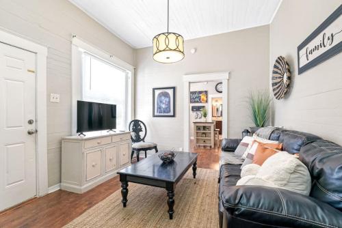 a living room with a black leather couch and a table at Charming and Historic Bungalow Near All in Tampa