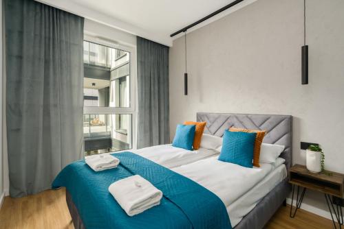 a bedroom with a large bed with blue and white pillows at Osiedle Goplana Apartment FREE GARAGE by Renters in Poznań