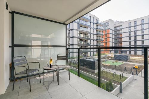 a balcony with a table and chairs and a large window at Osiedle Goplana Apartment FREE GARAGE by Renters in Poznań