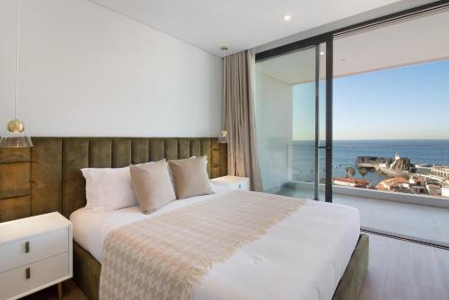 um quarto com uma cama e vista para o oceano em Sunset Bliss Apartment em Câmara de Lobos