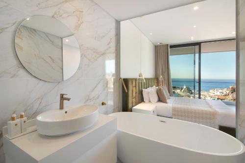 un bagno con vasca e lavandino e una camera da letto di Sunset Bliss Apartment a Câmara de Lobos