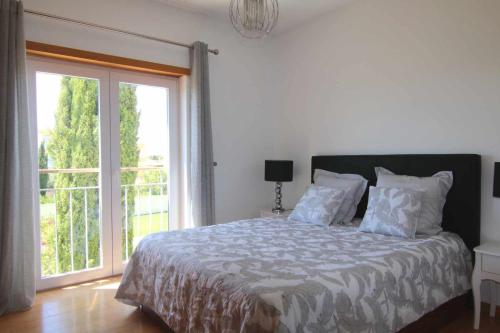 ein Schlafzimmer mit einem Bett und einem großen Fenster in der Unterkunft Golf Mar Village By Vilamoura Sun Vista Golfe in Vilamoura