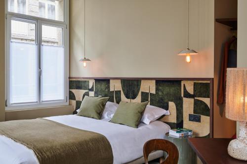 a bedroom with a bed and a desk and a window at Hôtel Cartier in Saint Malo