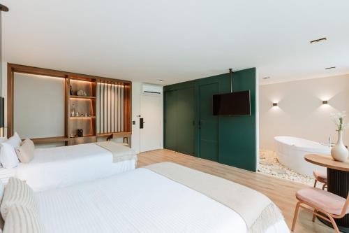two beds in a bedroom with a tub and a bathroom at 1616 Hotel in Medellín