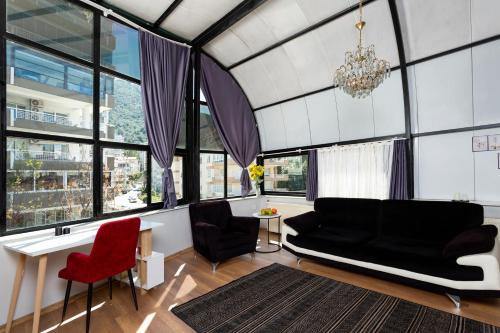 uma sala de estar com um sofá preto e cadeiras vermelhas em 8 Rooms House em Balçova