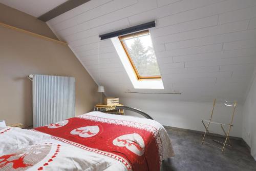 ein Schlafzimmer mit einem Bett im Dachgeschoss mit einem Fenster in der Unterkunft Gîte Le Bijou et Spa in Weiterswiller