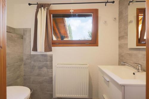 baño con lavabo y aseo y ventana en Le Chalet Cosy piscine et spa, en Weiterswiller