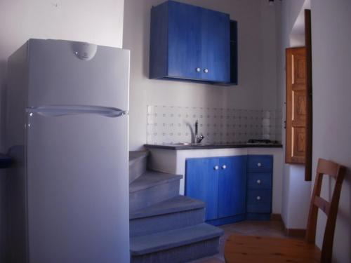 kuchnia z niebieskimi szafkami i białą lodówką w obiekcie Casa Celeste w mieście Lipari