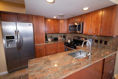 a kitchen with wooden cabinets and a stainless steel refrigerator at Winterplace on Okemo Mountain in Ludlow