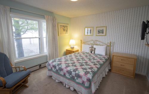 a bedroom with a bed and a chair and a window at Winterplace on Okemo Mountain in Ludlow