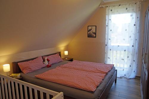 a bedroom with a bed with a red comforter and a window at Ferienwohnungen am Roten Nil in Lübben