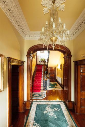 a hallway with a chandelier and a stairway at Elm Grove Country House in Tenby