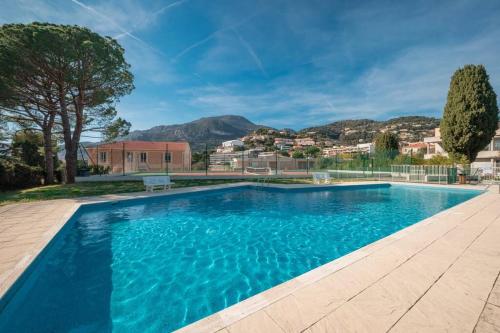a large swimming pool with blue water at Appartement familial 6P, avec piscine et tennis, proche mer in Roquebrune-Cap-Martin