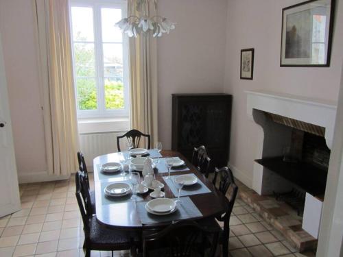 a dining room with a table with chairs and a fireplace at Maison Aunac in Aunac