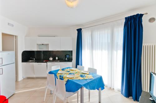 comedor con mesa azul y sillas en Villa Marina Apartments - Agenzia Cocal, en Caorle