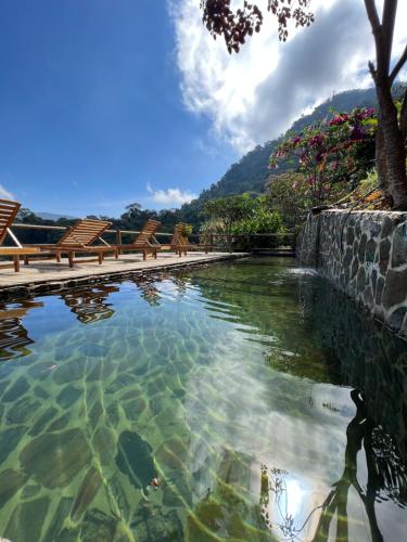 a pool of water with some chairs in it at Loma Nevada Minca Hotel in Minca