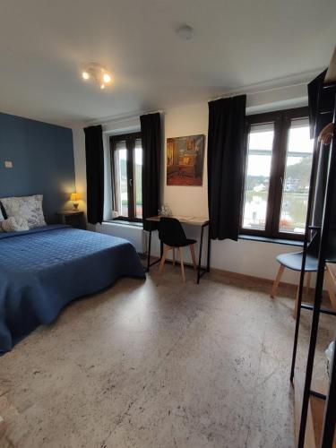 a bedroom with a bed and a desk and windows at Au Rocher in Dinant