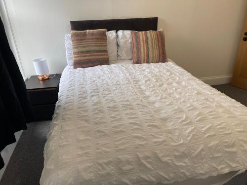 a bed with a white comforter and a side table at Lovely room in Bristol 5 in Bristol