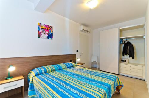 ein Schlafzimmer mit einem Bett mit einer blauen und gelben Tagesdecke in der Unterkunft Villa Marina Apartments - Agenzia Cocal in Caorle