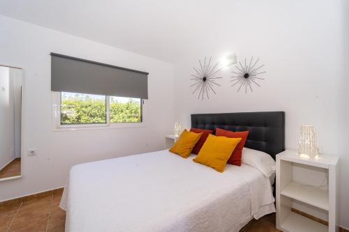 um quarto com uma cama branca e almofadas laranja em Apartamento Jibazahora Libra em Zahora