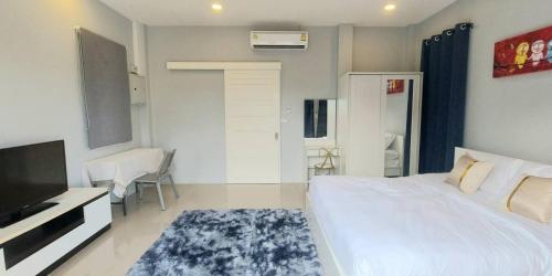 1 dormitorio con 1 cama blanca y TV en Patrick villa phuket, en Bang Tao Beach