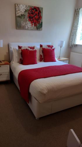 a bedroom with a large bed with red pillows at Buckley Farmhouse B & B in Sidmouth