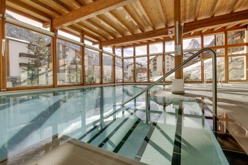 a swimming pool in a building with windows at Hotel Metropol & Spa Zermatt in Zermatt