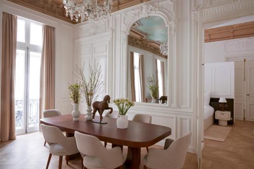 uma sala de jantar com uma mesa, cadeiras e um espelho em Maison Delano Paris em Paris