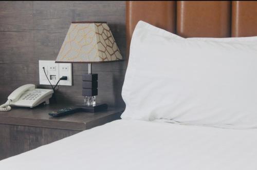 a bed with a lamp and a phone on a night stand at HAPPY HOTEL Tp Rạch Giá, Kiên Giang in Ấp Rạch Mẹo