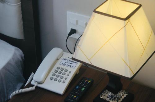 a phone sitting on a table next to a lamp at HAPPY HOTEL Tp Rạch Giá, Kiên Giang in Ấp Rạch Mẹo